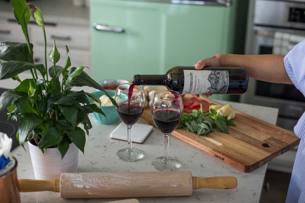 Lifestyle blogger Devin McGovern and wife Marlene Martinez in the kitchen with pizza and wine