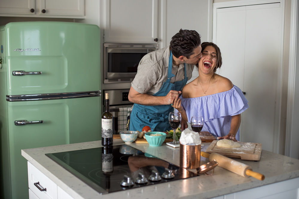 Lifestyle blogger Devin McGovern and wife Marlene Martinez in the kitchen with pizza and wine